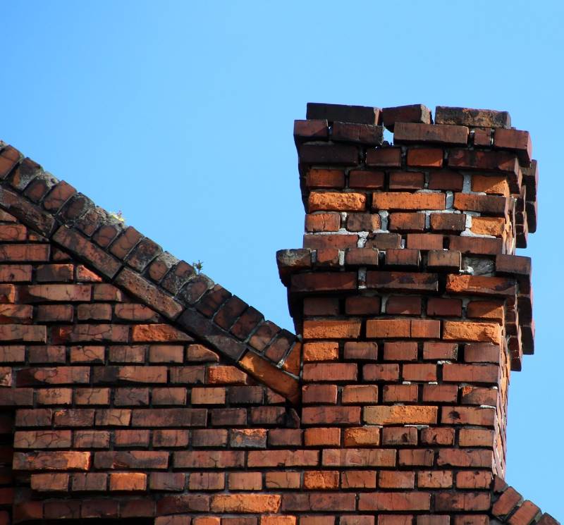 Damaged chimney on an Arlington home showing cracks and missing mortar